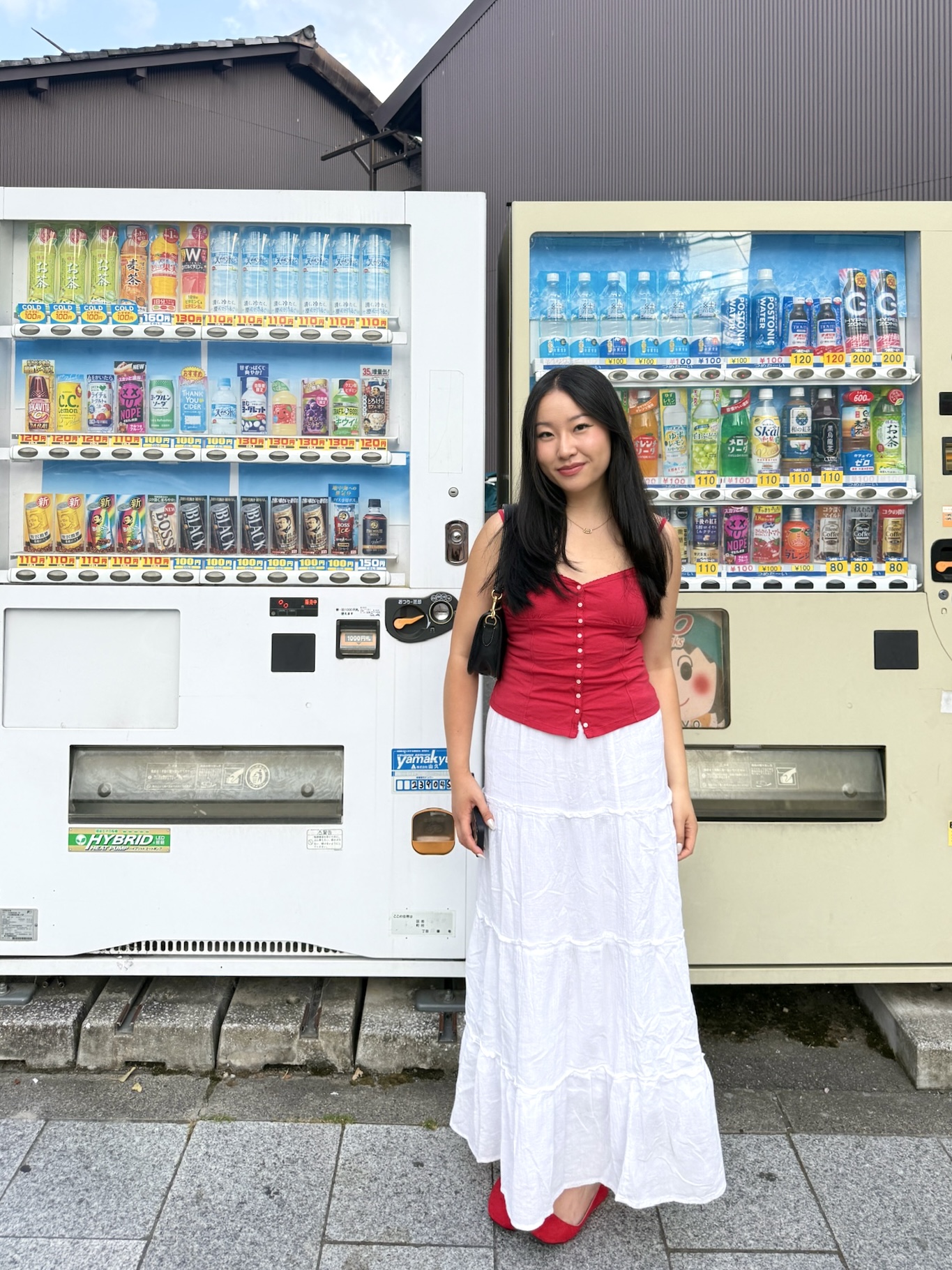Tina standing between two vending machines in Japan.