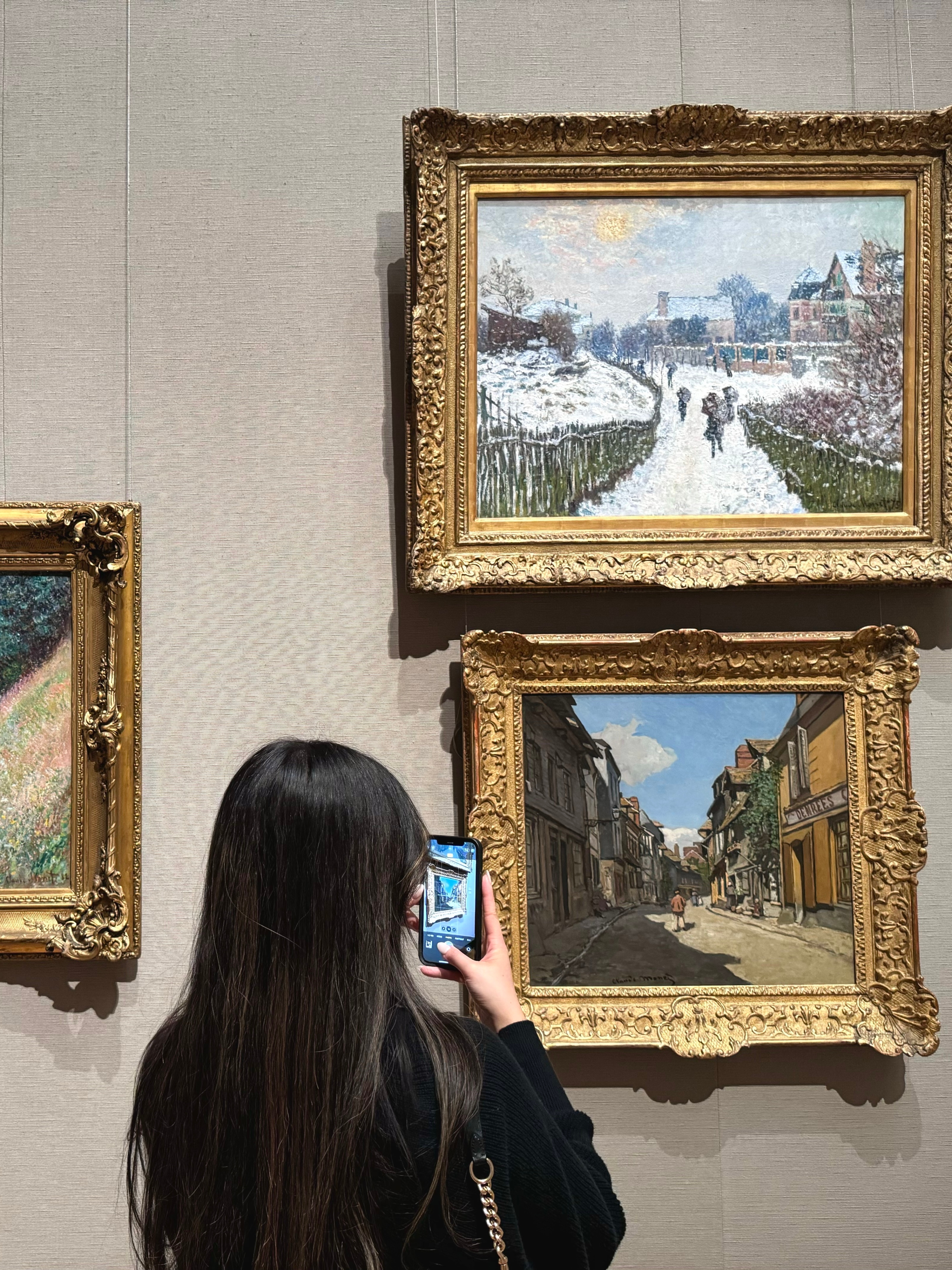 Tina photographing Impressionist paintings on a gallery wall.